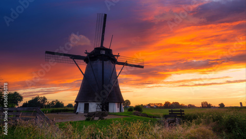 Windmills in the Netherlands. Historic buildings. Agriculture. Summer landscape during sunset. Bright sky and the silhouette of a windmill.