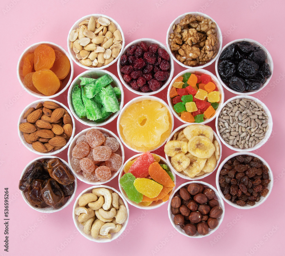 Nuts, seeds, dried fruits in round containers. Background with a mix of healthy snacks. Assorted vitamin food on a pink background. Nuts, seeds, dried fruits in round containers. Background with a mix of healthy snacks. Assorted vitamin food on a pink background.