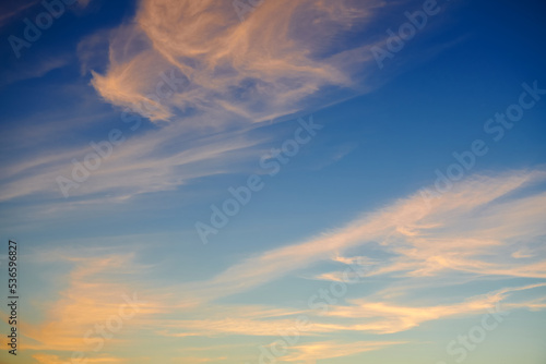 Wispy cirrus clouds. High orange wispy cirrus clouds expanding by wind to cover deep navy blue sky on sunset. photo