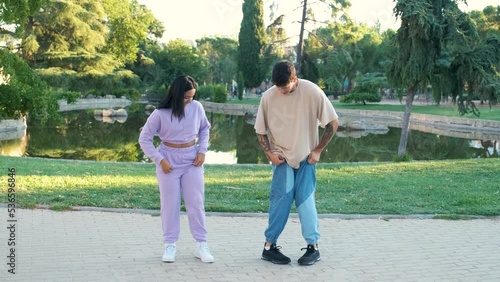Two young latin friends practicing a choreography and laughing at street in a park.