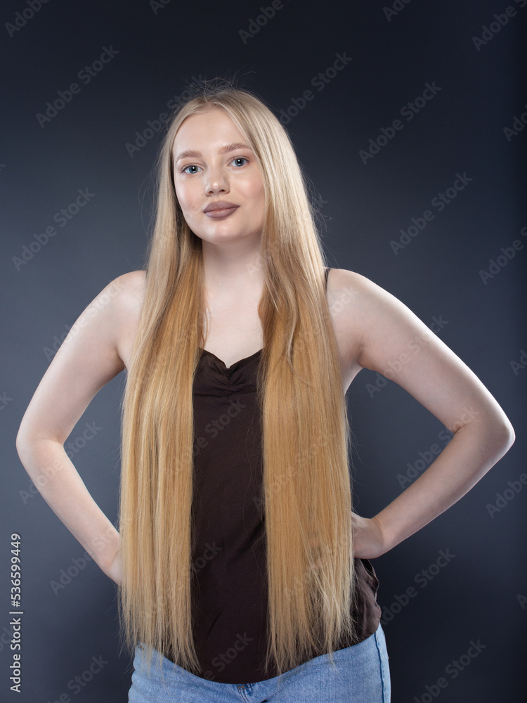 Young blonde woman in jeans and brown singlet on gray background Young blonde woman in jeans and brown singlet on gray background