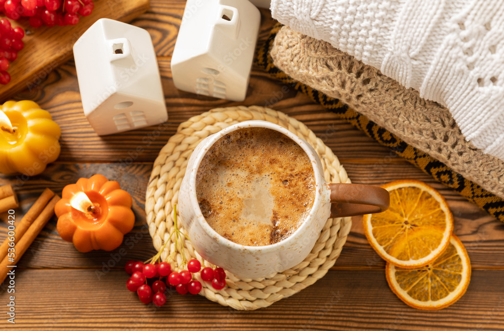 Autumn composition, a hot cup of coffee, candles, candlesticks, a miniature house and a warm sweater on a wooden table.Seasonal, morning hot coffee. Relaxing and still life concept.Cozy interior decor Autumn composition, a hot cup of coffee, candles, candlesticks, a miniature house and a warm sweater on a wooden table.Seasonal, morning hot coffee. Relaxing and still life concept.Cozy interior decor