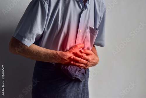 Asian man suffering from upper abdominal pain. It can be caused by stomach ache, enteritis, colitis, appendicitis, hepatitis, pancreatitis, food poisoning, etc.