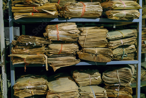 Shelves with old archival paper documents on rack in piles photo