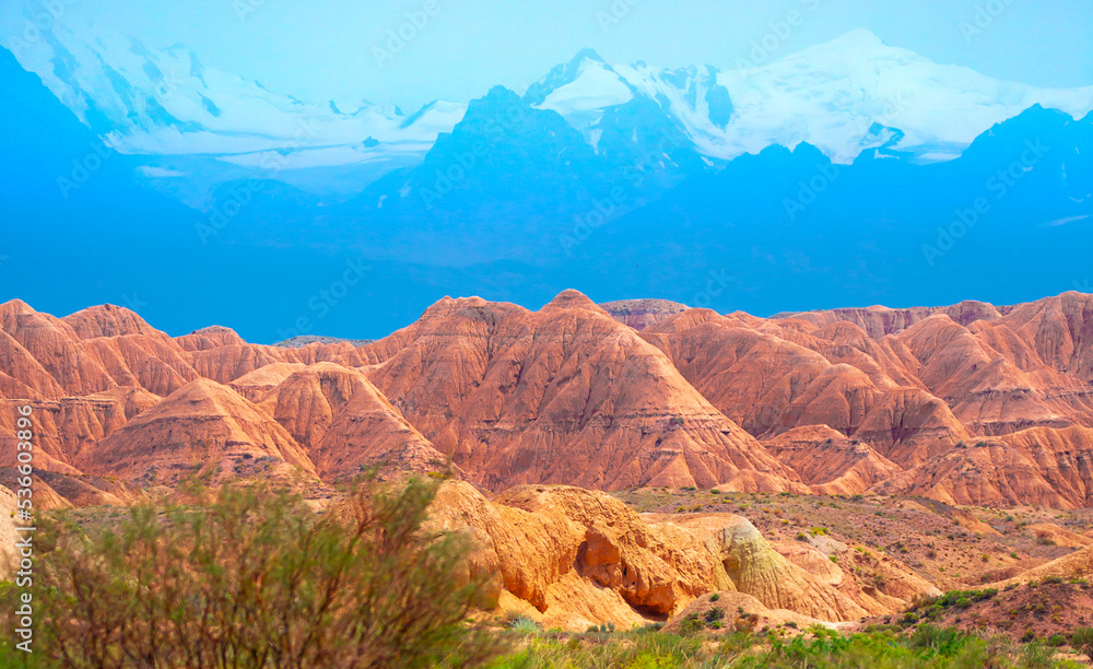 Fototapeta premium Natural unusual landscape of red rocks against the backdrop of blue mountains. The extraordinary beauty of nature is similar to the Martian landscape. Amazingly beautiful landscape.