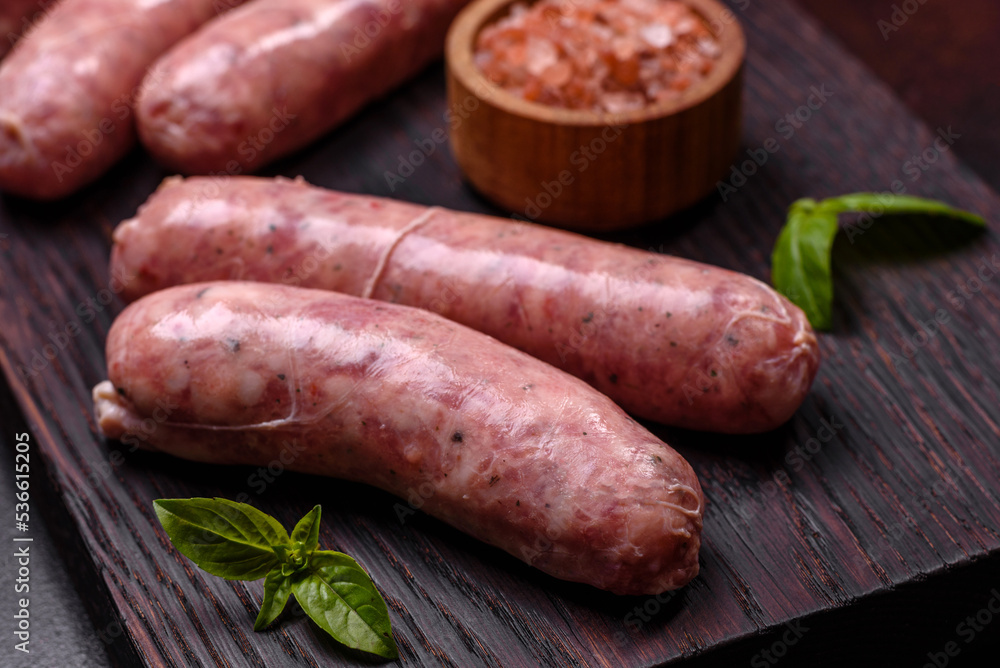 Raw sausages with ingredients on a cutting board on a dark concrete background with copy space Raw sausages with ingredients on a cutting board on a dark concrete background with copy space