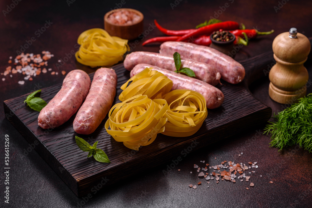 Raw sausages with ingredients on a cutting board on a dark concrete background with copy space Raw sausages with ingredients on a cutting board on a dark concrete background with copy space