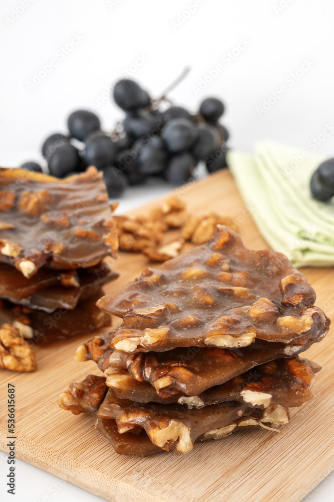 Lazy grape churchkhela with walnut on wooden board. Slices of fruit pastilla with nuts. Handmade sweet snack for healthy diet.
