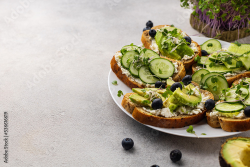 Vegetarian green sandwiches with avocado and cucumber with microgreens on a light background