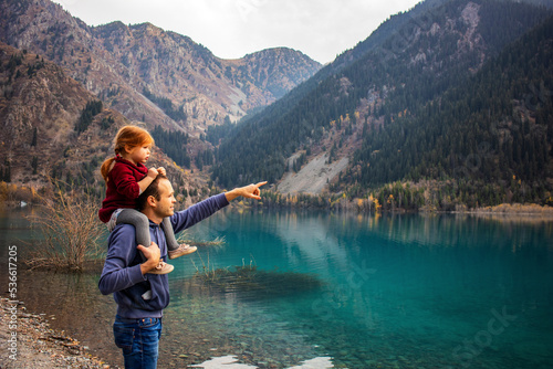 my daughter is around my dad's neck on a mountain lake. dad shows his daughter