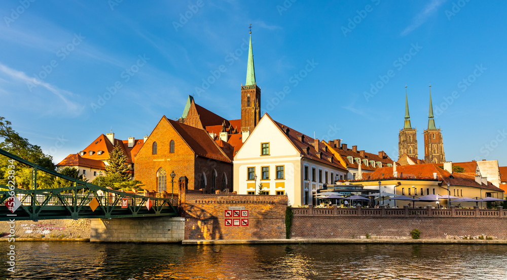 Panoramic view of Ostrow Tumski Island with Holy Cross collegiate and St. John Baptist cathedral over Odra river in historic old town quarter of Wroclaw in Poland Panoramic view of Ostrow Tumski Island with Holy Cross collegiate and St. John Baptist cathedral over Odra river in historic old town quarter of Wroclaw in Poland