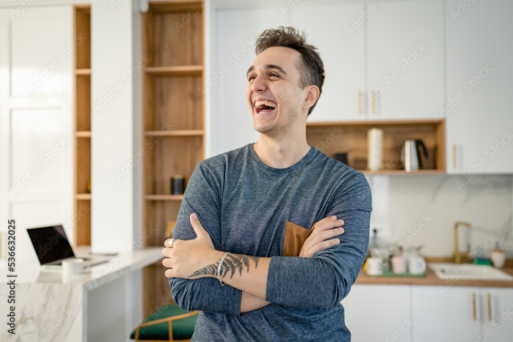 Front view portrait of one man young adult Caucasian male standing in the kitchen in day at home happy smile confident copy space waist up real people
