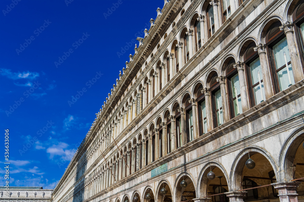 View of the renaissance façade of the Marciana Library from Piazza San Marco in the city of Venice on a sunny morning. Blue sky with white clouds. The largest library in Venice. Copy space