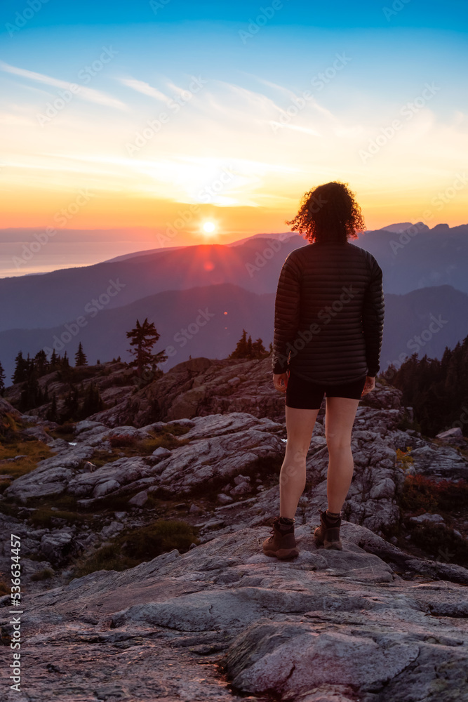 Fototapeta premium Adventurous Woman Hiker on top of Canadian Mountain Landscape. Sunny Sunset Sky. Top of Mt Seymour near Vancouver, British Columbia, Canada. Adventure Travel Concept