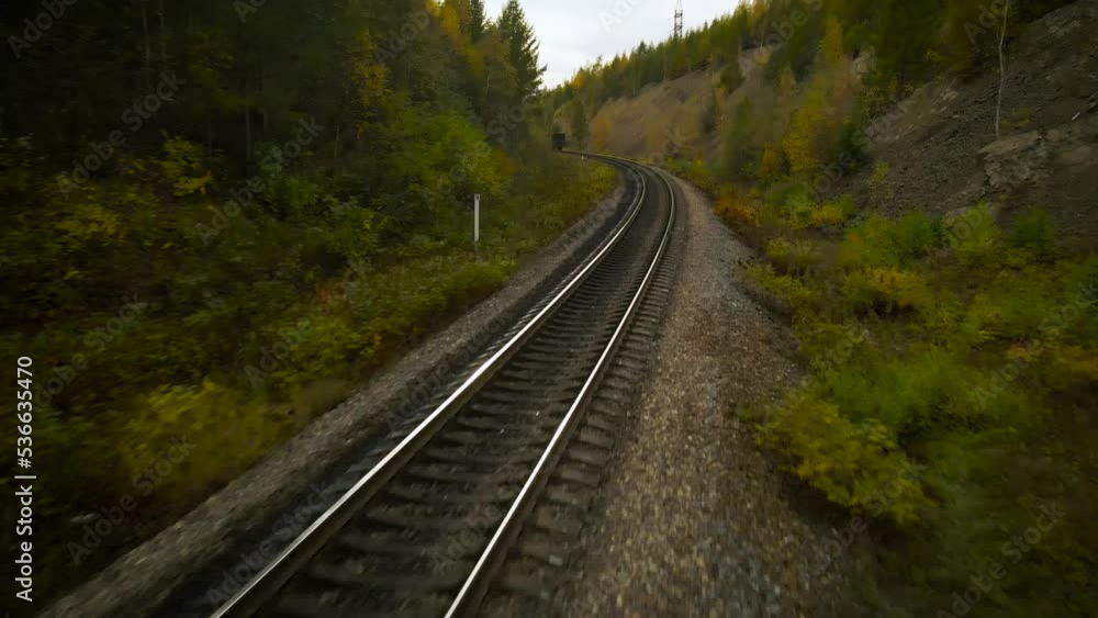 Aerial view of the railway and train next to the mountain covered beautiful gold autumn forest under cloud sky and sun Aerial view of the railway and train next to the mountain covered beautiful gold autumn forest under cloud sky and sun