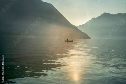 Fototapeta Naklejka Na Ścianę i Meble -  Idyllic  landscape on lake Como (a little fog)  with boat of fishier and small body of fisher at distance (unrecognizable person)