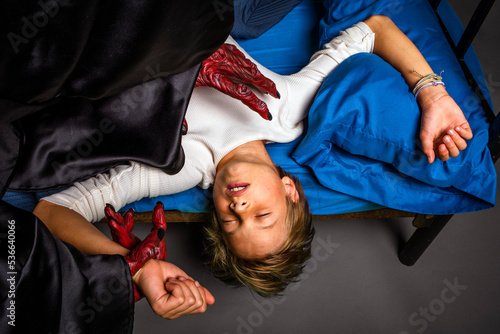 Fototapeta Young boy asleep in a bed is threatened by a scary monster