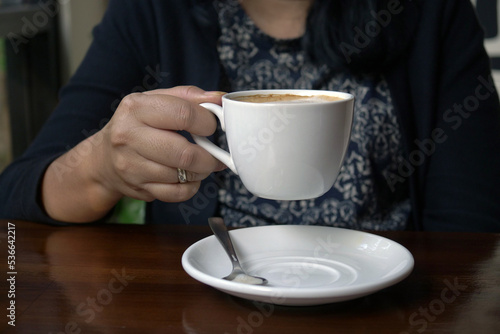 Close up of a woman's hand holding a cup of coffee