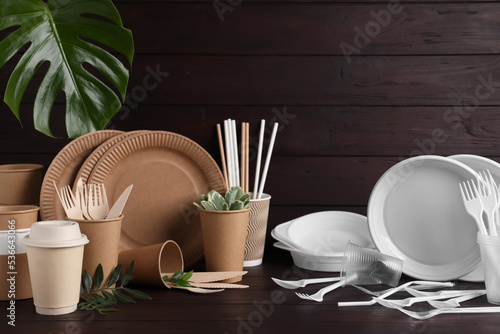 Plastic and eco disposable tableware on wooden table photo