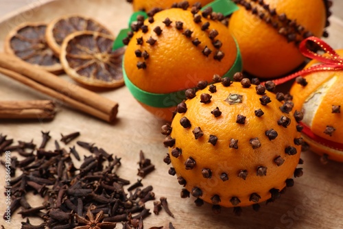 Pomander balls made of tangerines with cloves on wooden table, closeup photo