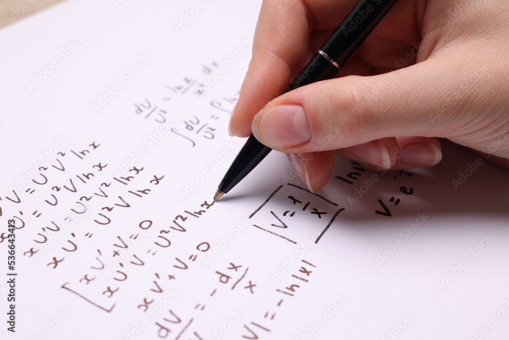 Student writing different mathematical formulas on paper, closeup Student writing different mathematical formulas on paper, closeup