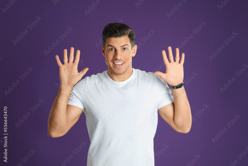 Man showing number ten with his hands on purple background Man showing number ten with his hands on purple background