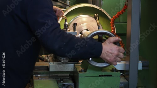 man is shaping steel in cnc lathe machine