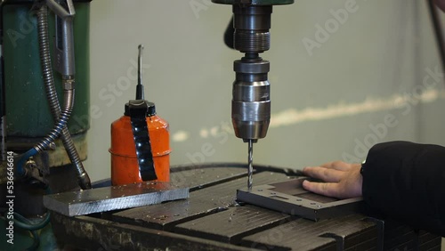 a piece of aluminium during lathing by a CNC drill. Fine cut end mill shaving the side of a matt block of metal. Micro machining process with old orange oil can
