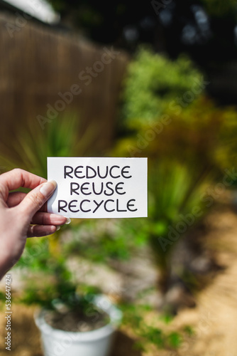 sustainability and circular economy, reduce reuse recycle sign in front of backyard bokeh