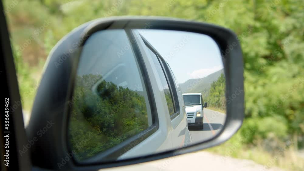View from car in rearview mirror, minivan is driving behind one car. need to look in side mirror. Car chase concept. Traveling in two cars in good company. View from car in rearview mirror, minivan is driving behind one car. need to look in side mirror. Car chase concept. Traveling in two cars in good company.