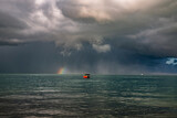 Little red boat under a storm cloud
