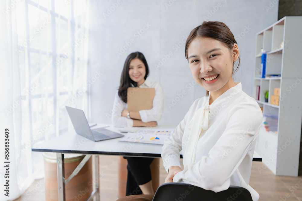 Two Asian businesswomen attending two Asian business partners discuss the financial and company planning graph during a budget meeting. Two Asian businesswomen attending two Asian business partners discuss the financial and company planning graph during a budget meeting.