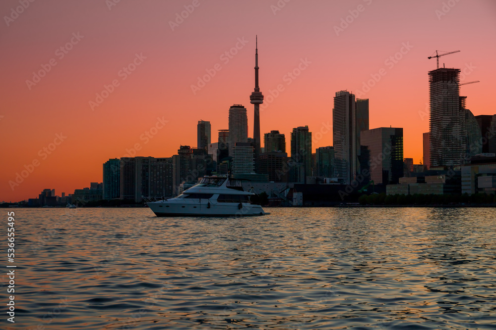 Toronto downtown cityscape with skyscrapers, white yacht and amazing color sunset sky