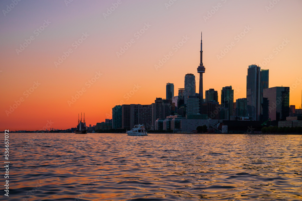 Toronto downtown cityscape with skyscrapers, white yacht, old sail ship and amazing color sunset sky