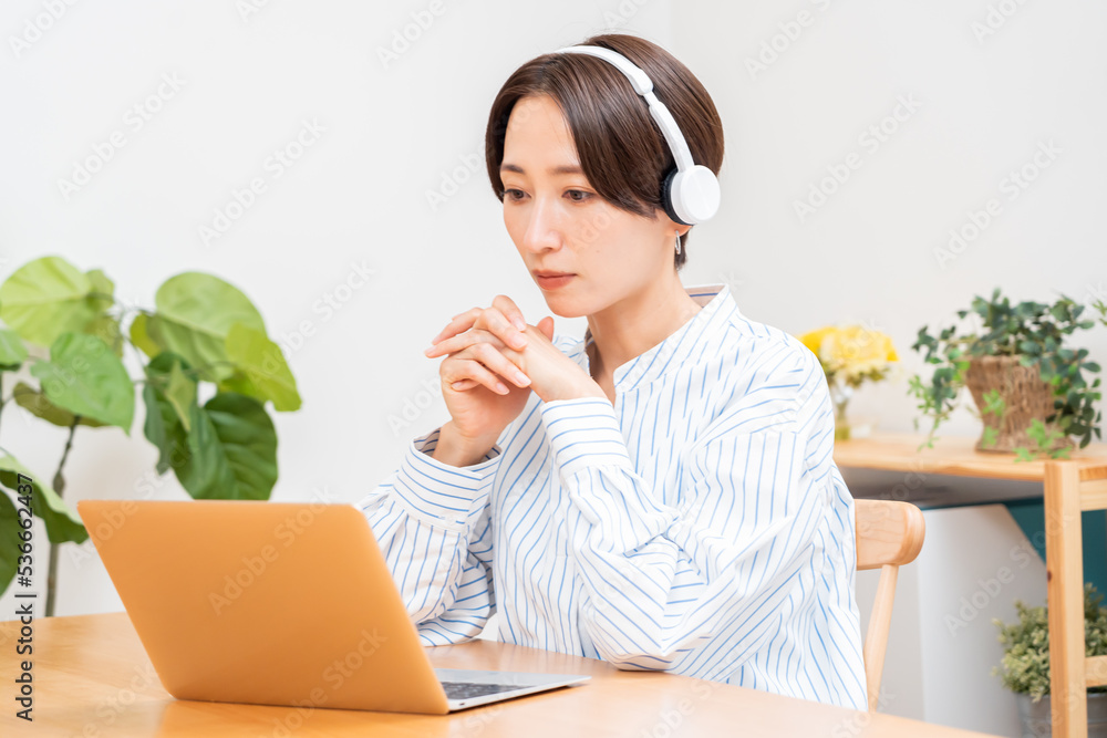パソコンを見るヘッドホンをつけたワンピースを着た日本人女性