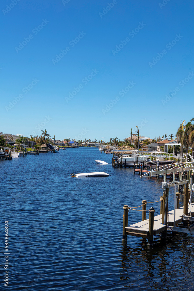Canal in Cape Coral Florida with damages and sunken boats due to Hurricane Ian. 