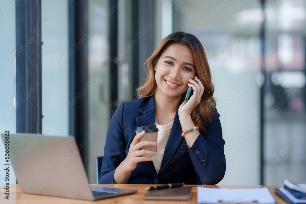 Smiling Asian businesswoman enjoying the phone, answering questions, talking to customers on the phone and comment in the office. Smiling Asian businesswoman enjoying the phone, answering questions, talking to customers on the phone and comment in the office.