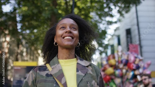 Attractive young female walking through a town with a big smiling expression, in slow motion