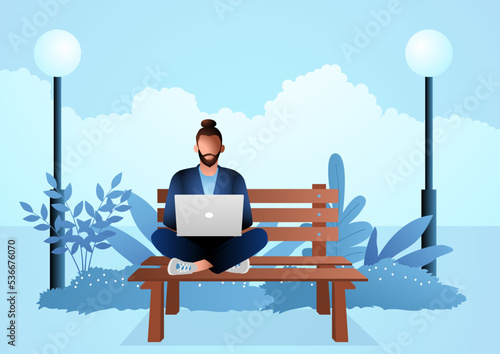 Young man sitting on wooden bench in the park while working with laptop