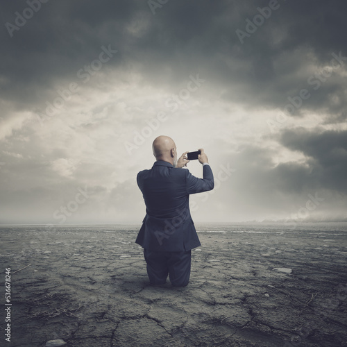 Businessman taking pictures of a barren land
