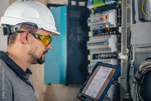 Man, an electrical technician working in a switchboard with fuses.