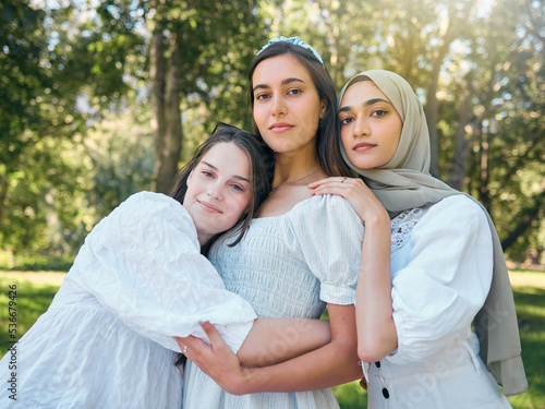 Group of women hug, show diversity, support and solidarity together, against forrest or garden background. Multicultural friends stand in unity, in outdoor portrait with trees or woods in backdrop © Mumtaaz D/peopleimages.com