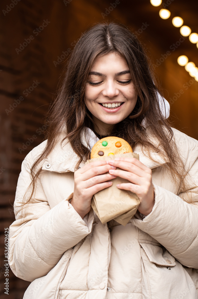Attractive young woman with gingerbread on a blurred background with bokeh. Attractive young woman with gingerbread on a blurred background with bokeh.
