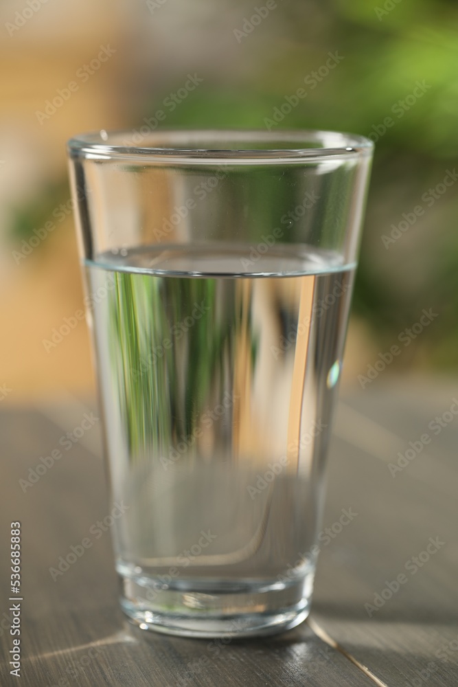 Glass of pure water on wooden table against blurred background, closeup Glass of pure water on wooden table against blurred background, closeup