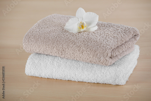 Soft folded towels with orchid flower on wooden table