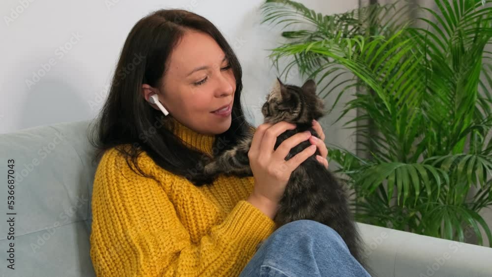 female with cute kitten relaxing at home wearing warm yellow sweater is resting with a cat on the armchair at home one autumn day. woman with cute cat relaxing at home