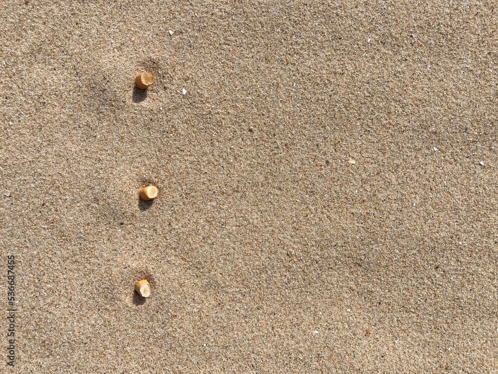 three cigarette butts arranged as bullet points in sand on beach three cigarette butts arranged as bullet points in sand on beach