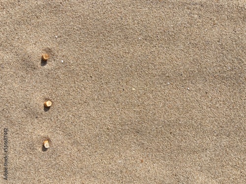 three cigarette butts arranged as bullet points in sand on beach