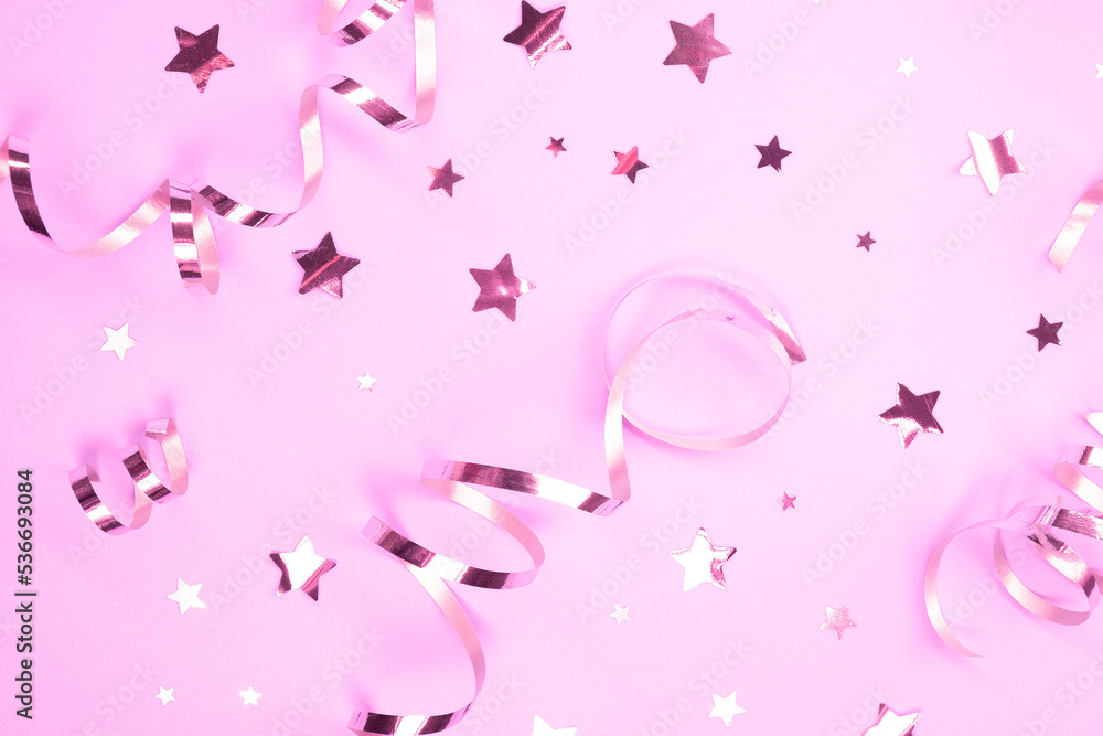 festive background with pink serpentine and confetti stars decorative, background. concept of a party or birthday party in pink colors or a newborn baby girl