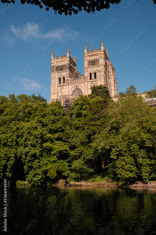 Durham England: 2022-06-07: Durham Cathedral exterior during sunny summer day. View from river wear with lush green trees